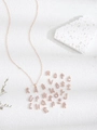 Detalle de colgantes de letras en oro rosa con cristales sobre una base de piedra blanca - Oro Rosa-A