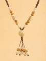 Detail van vintage bohemien kralenketting met kwastjes en etnische keramische elementen - Geel