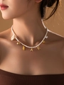 Detail of beaded shell necklace with gold charms and letter A on model neck - Letter A / White