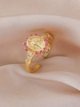 Macro-opname van gouden religieuze medaille ring met roze zirkonen op champagnezijde - Rood