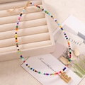 Collana bohémien in perline colorate con ciondolo a lettera E dorata e chiusura a moschettone - Lettera E