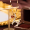 Close-up of golden necklace with crystal letter H pendant and red apple charm - Letter H