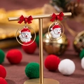 Vista dettagliata di orecchini natalizi con Babbo Natale e fiocchi rossi su supporto oro - Testa di Babbo Natale in cerchio con fiocco