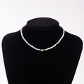 Detail shot of colorful macaron bead necklace featuring a gold heart pendant with letter C - Letter C
