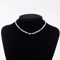 Detail showing rainbow seed bead necklace with gold heart pendant featuring engraved letter D - Letter D