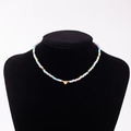 Rainbow bead necklace with gold heart pendant featuring letter M on black velvet stand - Letter M