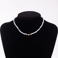 Rainbow seed bead necklace with gold heart pendant featuring the letter N on black mannequin - Letter N