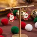 Orecchini di Babbo Natale in smalto rosso e bianco su un espositore per gioielli dorato - Babbo Natale che porta i regali
