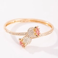 Eleganter goldfarbener Rosenknospen-Armreif mit rosa und weißen Strasssteinen auf Weiß - Doppelkopf Rose Armreif