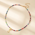 Collier en perles colorées avec pendentif lettre S dorée sur fond beige doux - Style Lettre S (S)