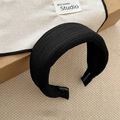 Close-up of black ribbed fabric headband with HAND MADE label on inner lining - Black