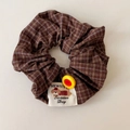 Détail d'un chouchou à carreaux café avec bouton jaune et étiquette en tissu chien - Chouchou