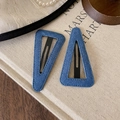 Detail of vintage navy denim triangle hair clips with neat stitching on book background - Denim Triangle Style