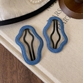 Close-up of wave-edge navy blue denim hair clips on a vintage book with pearls - Denim Cloud Style