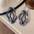 Detail view of retro navy blue plaid hollow hair clips on a textured beige background - Plaid Cloud Style