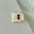 Detail of cute pearlescent acetate bear hair clip with a red 3D bow on fabric - Mermaid Color