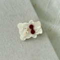 Macro shot of acetate bear hair clip with red bow on natural linen fabric background - Milk White
