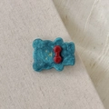 Süße Bären-Haarspange aus blauem Acetat mit roter Schleife auf Leinenhintergrund - Blau