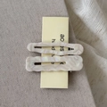 Detail of wavy acetate hair clips with pearl white marble texture on display card - Cream