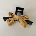 Detail of a black resin hair clip featuring a yellow and brown polka dot fabric bow design - Bow Claw Clip