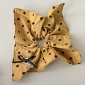 Detail view of yellow polka dot scrunchie with a brown leather bow and fabric label - Bandana