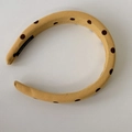 Macro shot of yellow polka dot fabric headband featuring a black handmade textile label - Headband