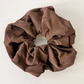 Close-up of deep brown leather texture scrunchie with litchi grain and Fashion label - Brown