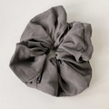 Detailed view of dark grey faux leather scrunchie with soft matte texture and fold design - Gray