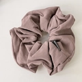 Detail of rose suede leather scrunchie with fashion label and textured pleated folds - Pink