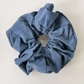 Detail of greyish blue leather-like scrunchie with soft pleats and Fashion label tag - Blue