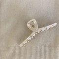 Detail shot of cream hair claw clip with rectangular rhinestones on knit background - Creamy White Cross Style