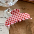 Detail einer rot-weiß karierten Haarklammer mit Gingham-Muster auf einer Holzoberfläche - Rot-Weißes Gingham-Stil