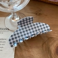 Detailansicht einer blau-weißen Haarklammer mit Karomuster auf einem Holztisch - Blau-Grau-Weißes Gingham-Stil