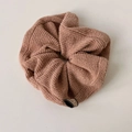 Close-up of brown knit scrunchie texture with a small Korea fabric brand tag - Pink Khaki