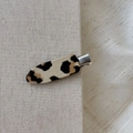Dettaglio di un fermaglio per capelli con stampa leopardata fissato su una tela ruvida - Leopardo Scuro (Stile B)