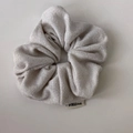 Dettaglio macro di uno scrunchie in maglia grigio chiaro scintillante con etichetta FMdrea - Bianco Sporco
