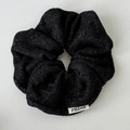 Primer plano de coletero negro brillante con hilos plateados y etiqueta de la marca - Negro