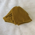 Detalle del tejido de terciopelo amarillo mostaza plisado en una pinza para el pelo - Amarillo