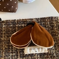 Dettaglio molletta in velluto marrone scuro con etichetta in tessuto su sfondo tweed - Marrone Arancio