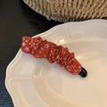 Detail of red floral fabric banana hair clip on a vintage decorative ceramic plate - Red