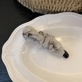 Detailed view of grey pleated chiffon banana hair clip on a white vintage plate - Black and White Print