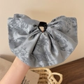 Dettaglio della pinza per capelli con fiocco in raso jacquard grigio e trama floreale - Blu Grigio