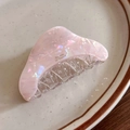 Detail of pink acetate hair claw with pearlescent marble texture on a ceramic plate - Pink