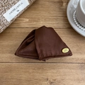 Detail of elegant dark brown satin fabric hair claw clip with a golden brand metal logo tag - Brown