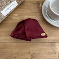 Close-up of elegant burgundy satin fabric hair claw clip with golden brand logo plaque - Red