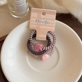 Close-up of three colorful spiral hair ties with star charms on a decorative ceramic plate - Three-Piece Set / Dark Purple Series