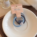 Detailed view of three spiral hair ties with star and heart charms on a white ceramic plate - Three-Piece Set / Blue Series