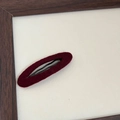 Dettaglio della clip ovale bordeaux con finitura floccata e robusta struttura in metallo - Rosso Ovale