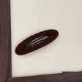 Close-up of a minimalist oval felt BB hair clip in dark coffee brown on wooden background - Dark Brown Oval