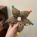 Dettaglio dell'elastico a stella leopardato con pompon colorati ed etichetta tessuta - Stampa leopardata